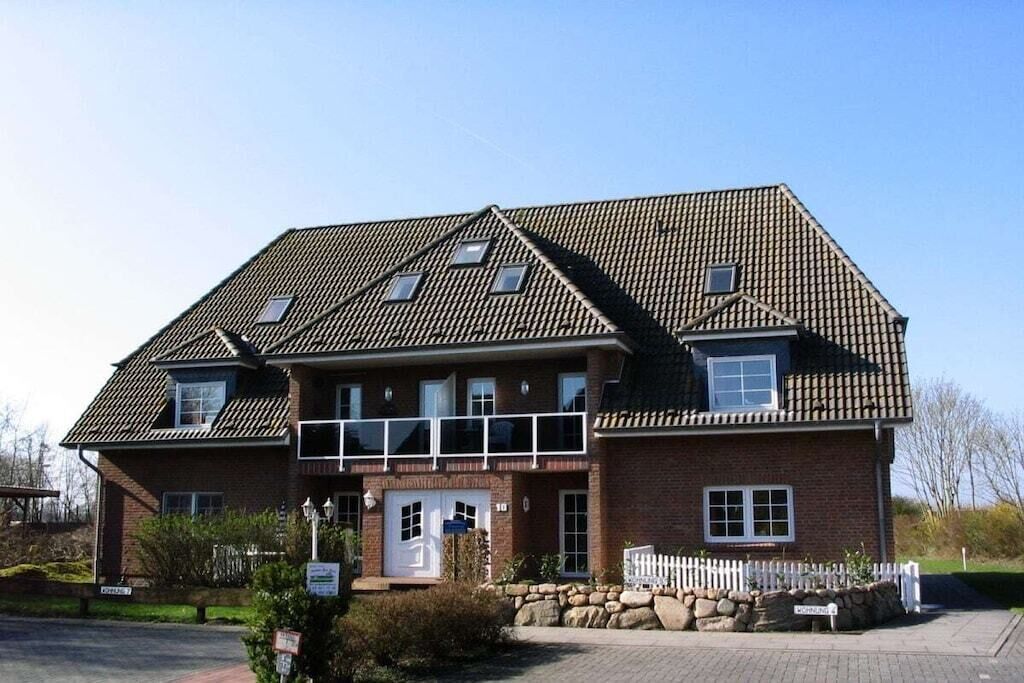 Ein zweigeschossiges Gebäude mit Satteldach, Hauseingang und einer kleinen Veranda.
