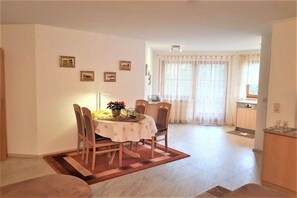 A dining area with a table set for four, chairs, a rug, and a kitchen in the background. - House on the Gutach River No. 07 (Titisee- Neustadt)