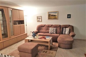 Una sala de estar con un sofá marrón, una mesa de centro y un aparador con puertas de vidrio.