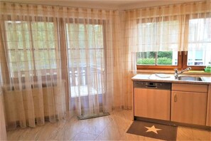 A kitchen with a dishwasher, a sink, and a window with curtains. - House on the Gutach River No. 07 (Titisee- Neustadt)