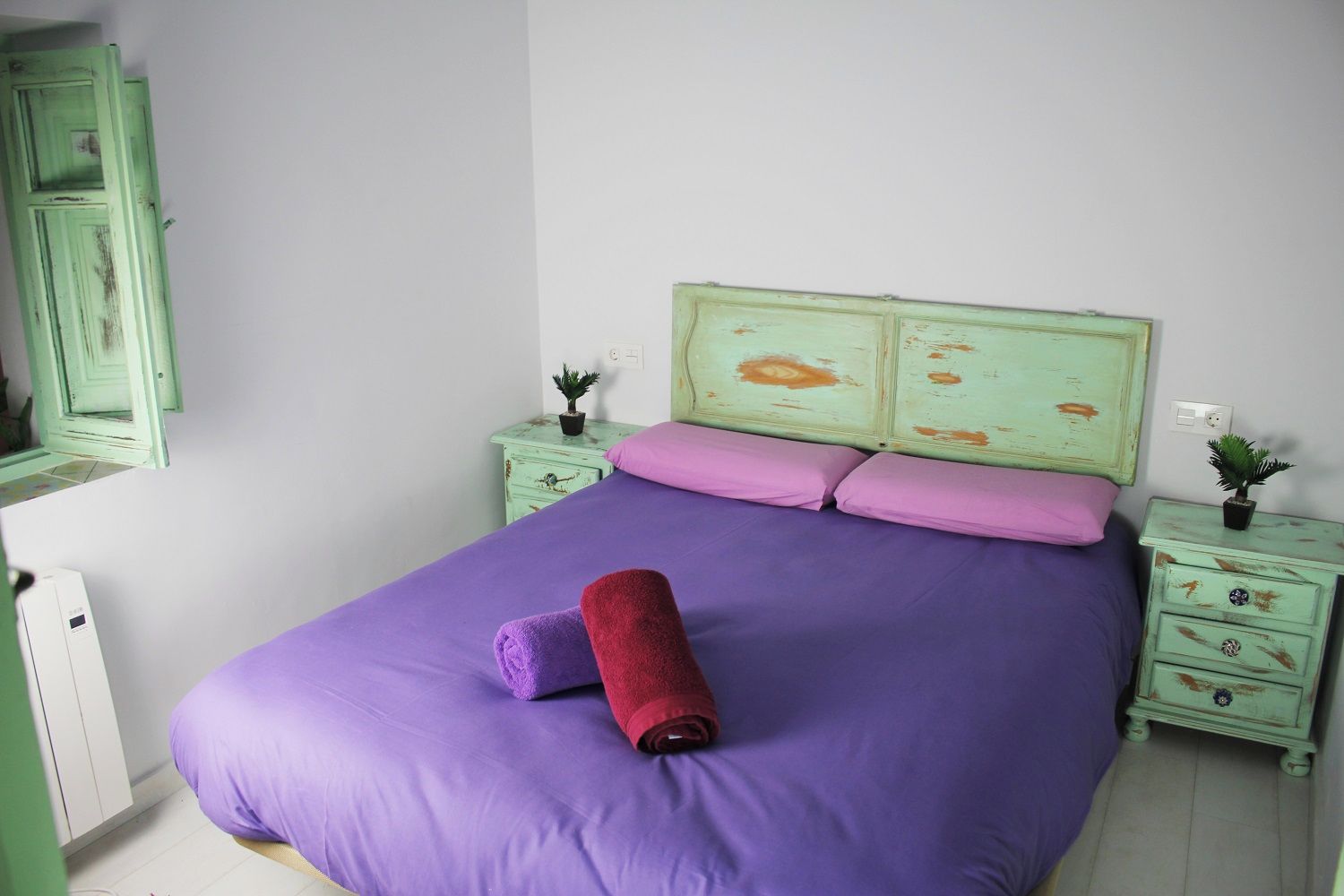 A bedroom with a bed, two nightstands, a dresser, and a mirror.