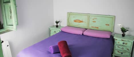 A bedroom with a bed, two nightstands, a dresser, and a mirror.