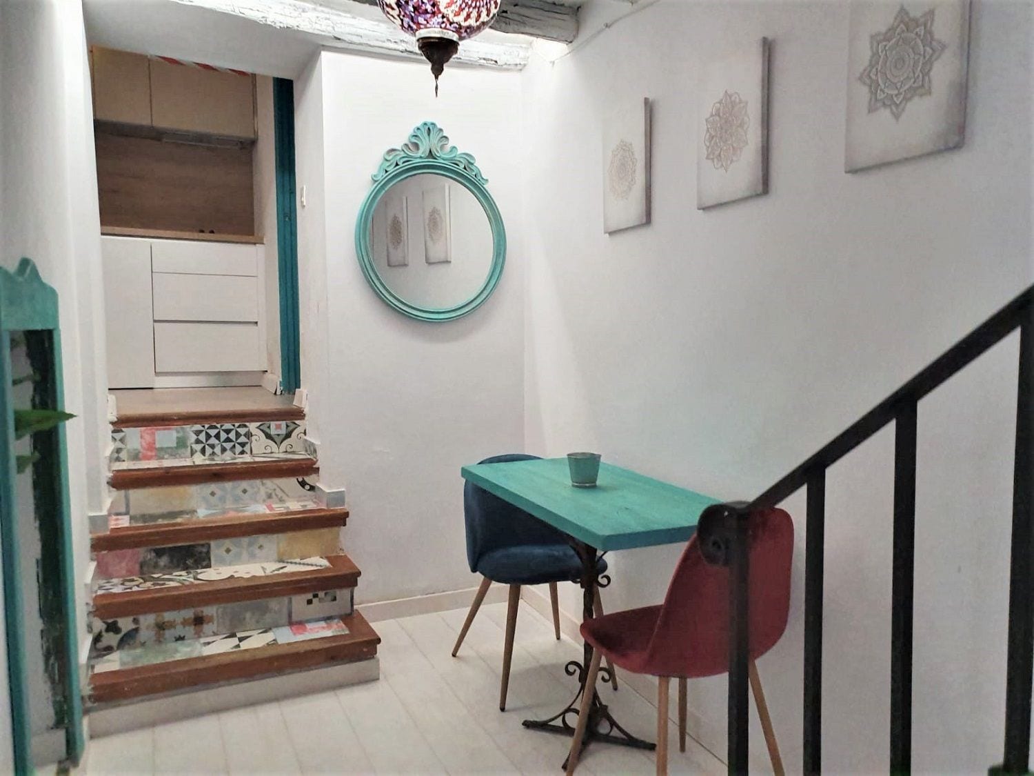 Una escalera con baldosas estampadas que lleva a un comedor con una mesa y sillas.