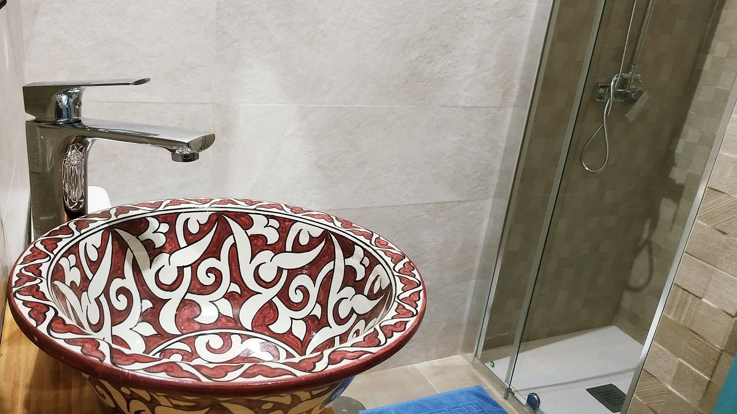 Une salle de bain dotée d’un lavabo décoratif en céramique et d’une cabine de douche en verre.