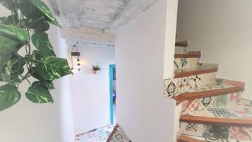 A staircase with patterned tiles and a wooden handrail, leading to a room with a blue door.