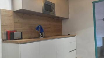 Una cocina con microondas, encimera de madera y armarios blancos.