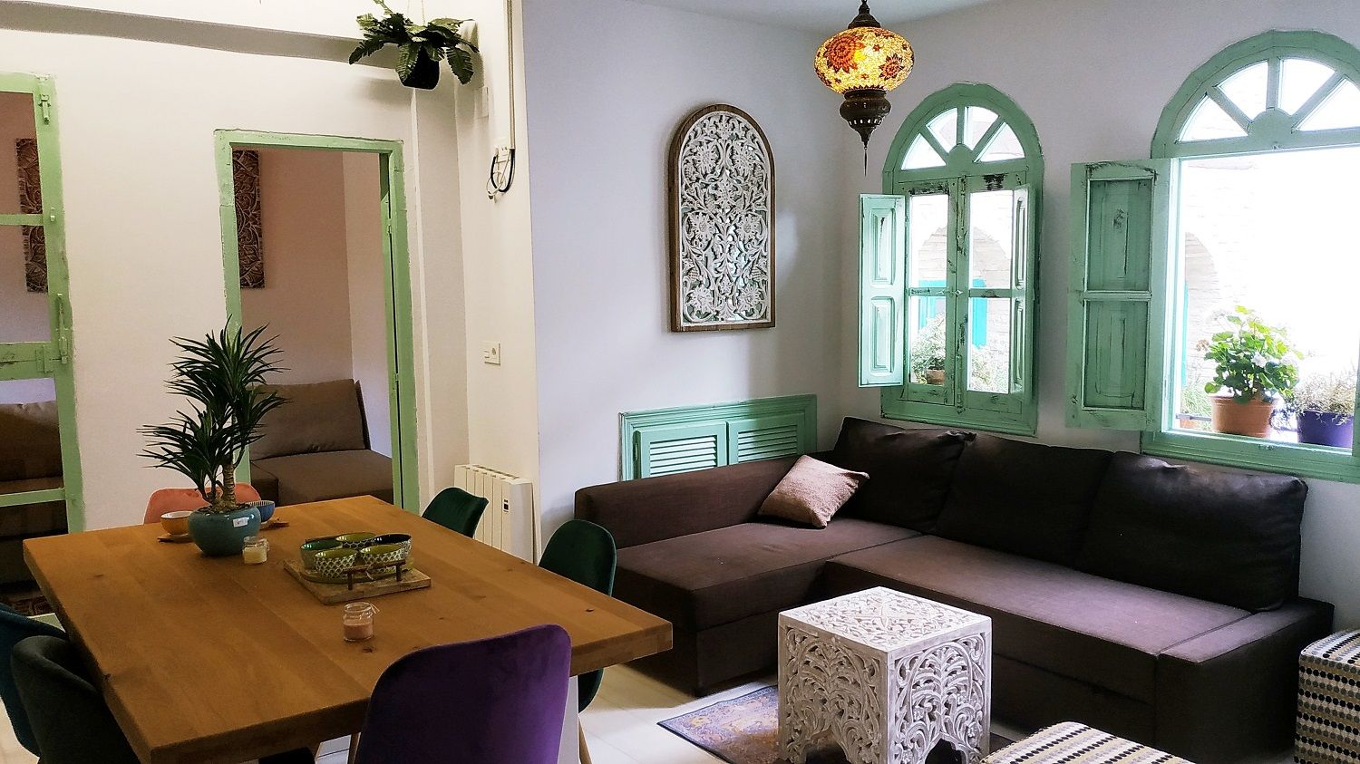 A cozy living room with a wooden table, a brown sofa, and a patterned wall decoration.