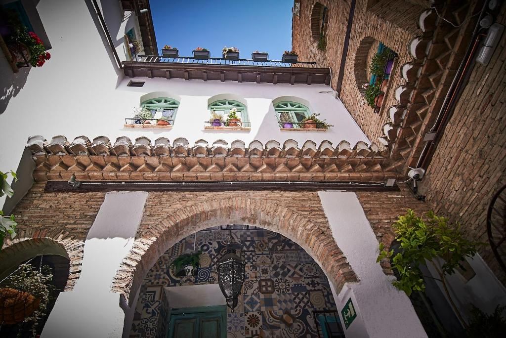 A courtyard with a tiled roof, a patterned archway, and a view of a building with a balcony.