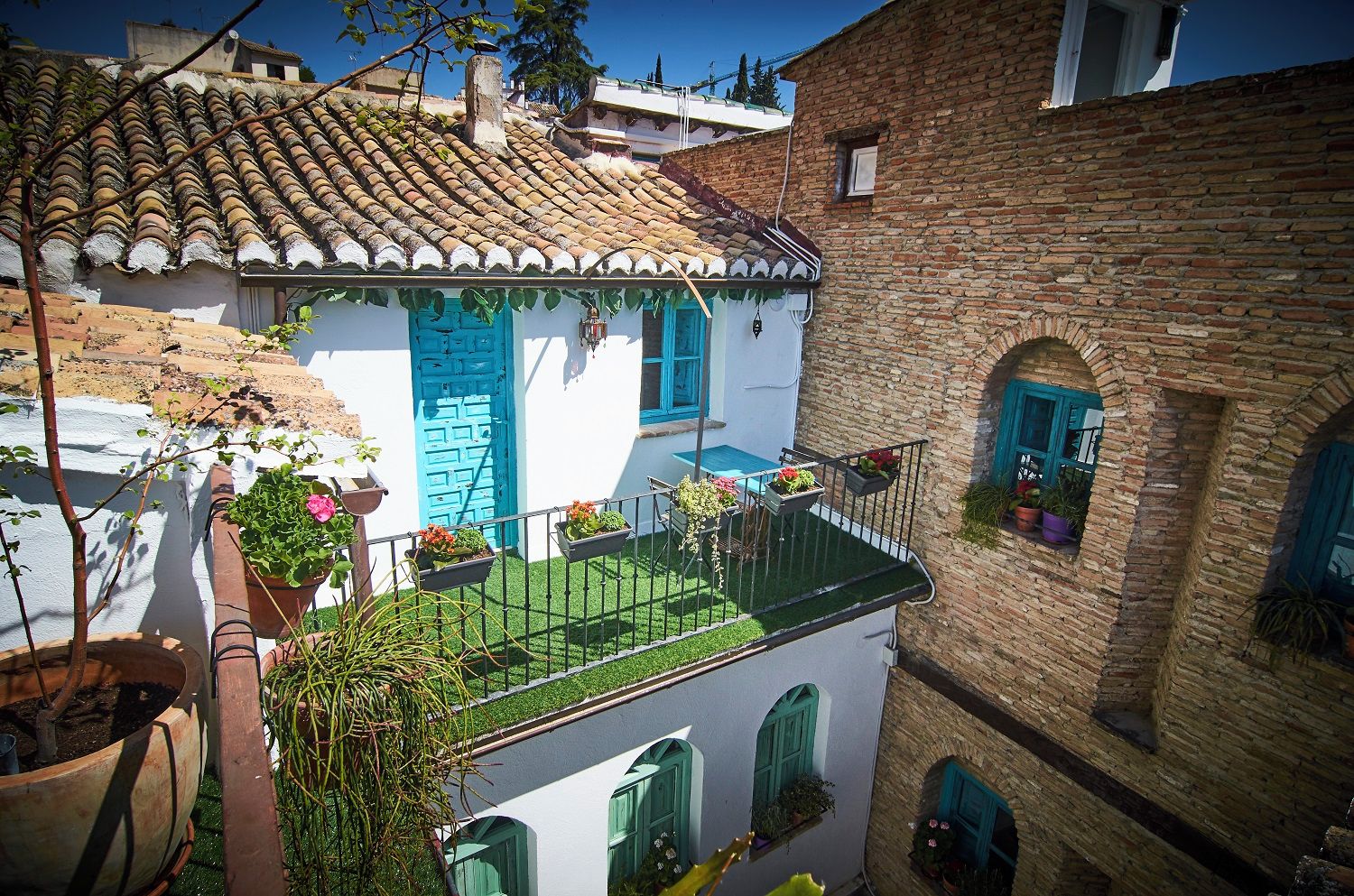 A traditional building with a tiled roof, a balcony with potted plants, and a blue door.