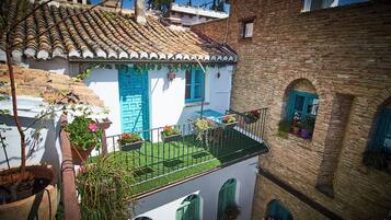 A traditional building with a tiled roof, a balcony with potted plants, and a blue door.