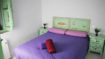 Een kamer met een bed, twee nachtkastjes, een groene dressoir en een kleine potplant.