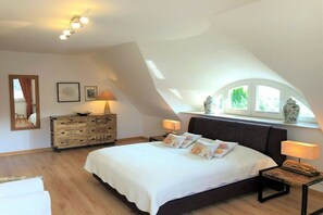Ein Schlafzimmer mit einem großen Bett, einem Schminktisch, einem Nachttisch und einem Fenster mit Blick.