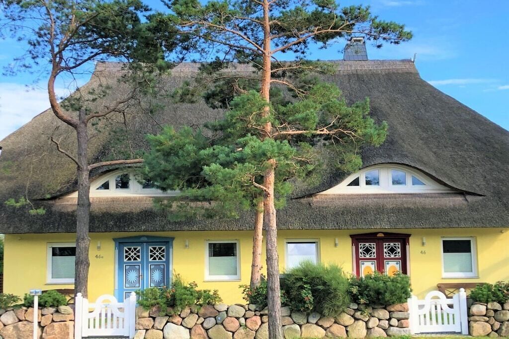 Ein traditionelles Haus mit einem strohgedeckten Dach, einem Stein Fundament und einer gelben Fassade.