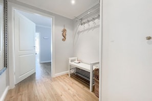 A hallway with a white door, a coat rack, and a small bench with a basket. - Holiday apartment with 1 bedroom (Timmendorfer Strand)