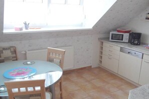A small kitchen with a round table, chairs, a microwave, and a coffee maker. - Holiday apartment with 2 bedrooms (Schönefeld)