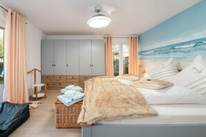 Une chambre à coucher comprenant un lit, une table de chevet, une armoire et une fresque murale sur le thème de la plage.