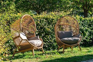 Two wicker chairs with cushions in a garden setting. - Holiday apartment in Baabe with swimming pool (Baabe)