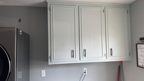 Eine Küche mit weißen Schränken, einem Kühlschrank und einer Wandleuchte.