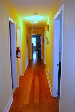 A hallway with wooden flooring, white walls, and a ceiling light fixture. - Spacious 4-bedroom house in fantastic Columbus with AC and gym (Columbus)