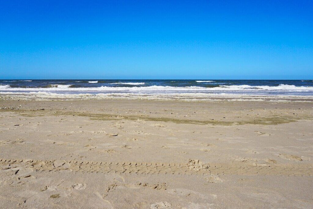 A beach with visible footprints and waves.