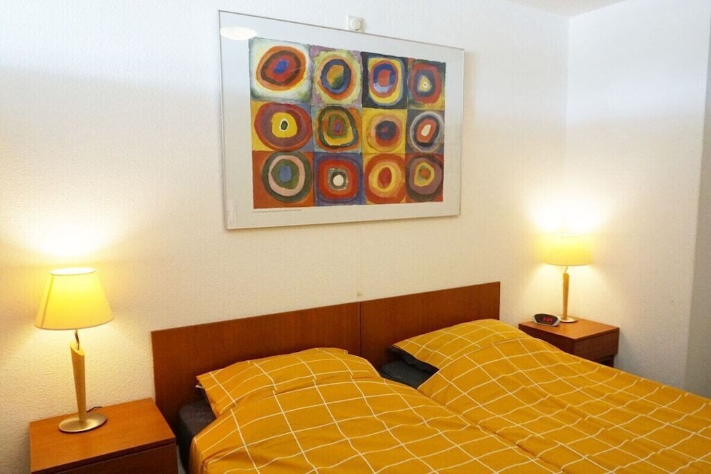 Een hotelkamer met een bed, twee nachtkastjes, een schilderij aan de muur en twee lampen.