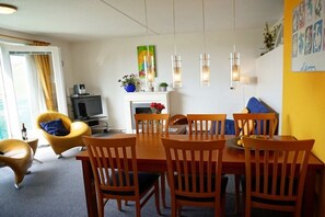Ein Essbereich mit Holztisch und -stühlen, einem Fernseher und einem Kamin.
