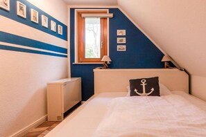 A bedroom with a bed, a window, a radiator, and wall-mounted lamps. - Holiday home with 3 bedrooms (Ostseebad Wustrow)
