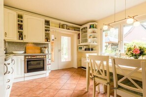 A kitchen with white cabinets, a wooden countertop, and a dining area with a table and chairs.
