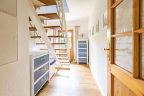 A hallway with a wooden staircase, a blue cabinet with drawers, and a wooden door with glass panels. - Holiday home with 3 bedrooms (Ostseebad Wustrow)