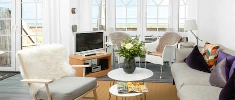 A modern living room with a sofa, chairs, a coffee table, and a TV.