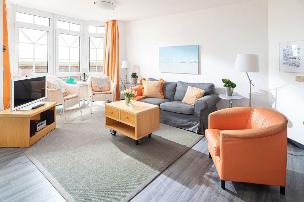 Un salon moderne avec un canapé, un fauteuil et un meuble pour la télévision.