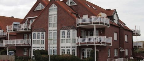 A large brick building with multiple balconies and a central entrance.