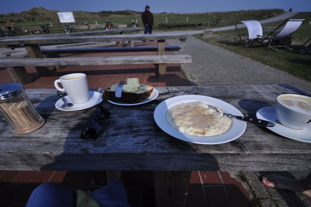 Une table de pique-nique avec une tasse de café, une assiette de nourriture et un pot de sucre.
