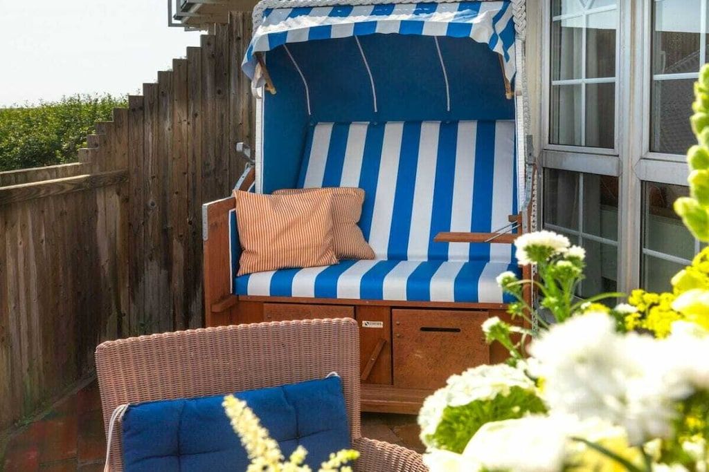 Une chaise de plage avec un coussin à rayures et une petite table, placée sur une terrasse en bois.