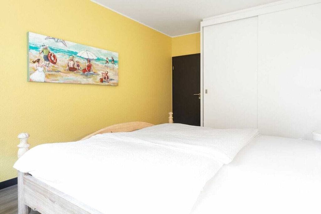 Een slaapkamer met een bed, een schilderij aan de muur en een deur.