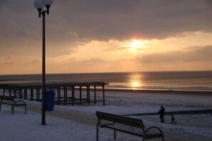 A beach with a wooden pier, benches, and a lamppost. - Schütz in the house "Kiebitzwiese" (Borkum)