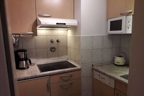 Una cocina compacta con estufa integrada, microondas y hervidor.