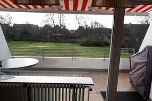 A balcony with a view of a grassy area and houses. - Schütz in the house "Kiebitzwiese" (Borkum)