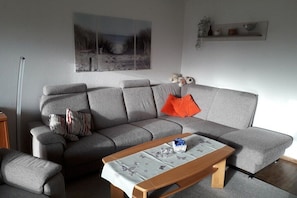 Ein Wohnzimmer mit grauem Sofa, einem Holztisch und einem Bild an der Wand.