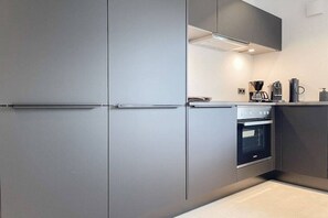 A modern kitchen with grey cabinetry, a built-in oven, and a coffee maker. - Holiday home with 4 bedrooms (Timmendorfer Strand)