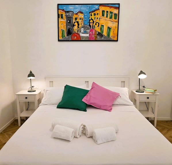A neatly made bed with white linens, two bedside lamps, and a painting above. - Domus 39 by Be Your Home (Civitavecchia)
