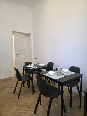A dining area with a table set for four, black chairs, and a white door in the background. - Domus 39 by Be Your Home (Civitavecchia)