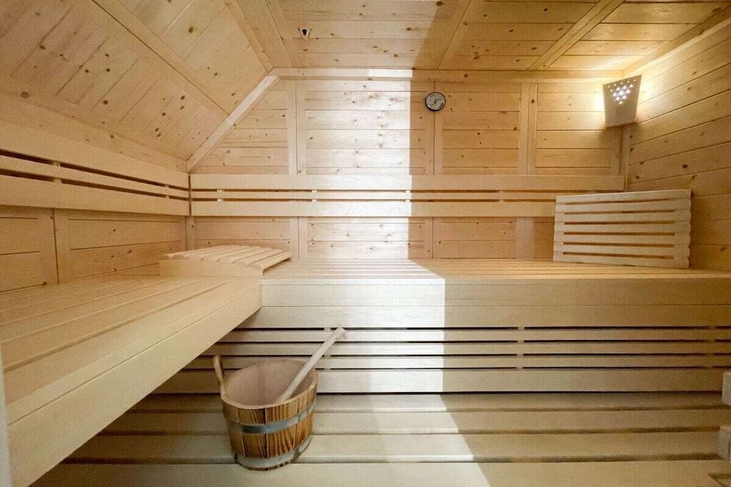 Eine Sauna mit Holzbänken, schrägstem Boden und einem Eimer.