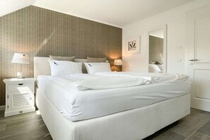 A modern bedroom with a large bed, bedside tables, and a mirror. - Holiday home with 3 bedrooms (Timmendorfer Strand)
