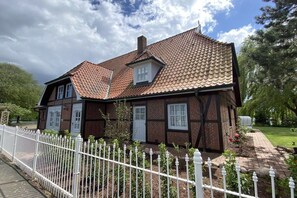 A two-story house with a tiled roof, a white picket fence, and a brick exterior. - Landhaus Lotten - Exclusive (Winsen)
