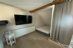 A small, single-room apartment with a bed, a television mounted on the wall, a radiator, and a small white table. - Holiday apartment in Waren with swimming pool (Waren)