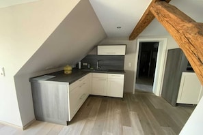 A kitchen with a modern design, featuring a grey countertop, white cabinets, and a wooden ceiling beam. - Holiday apartment in Waren with swimming pool (Waren)