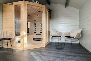 Ein Saunaraum mit Holzwänden, einer Glastür und zwei Korbsesseln.
