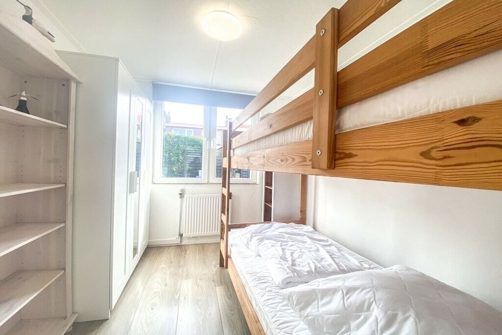 A bunk bed room with a window, white walls, and a radiator.