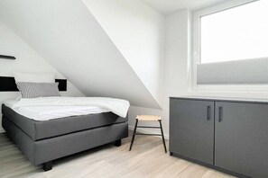 A modern bedroom with a bed, a small stool, and a cabinet. - Holiday home with 4 bedrooms (Timmendorfer Strand)